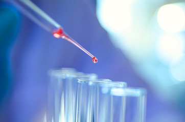A pipette dropping sample into a test tube,abstract science background