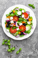 Greek salad. Fresh vegetable salad with tomato, onion, cucumbers, pepper, olives, lettuce and feta cheese. Greek salad on plate