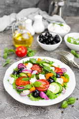 Greek salad. Fresh vegetable salad with tomato, onion, cucumbers, pepper, olives, lettuce and feta cheese. Greek salad on plate