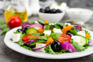 Greek salad. Fresh vegetable salad with tomato, onion, cucumbers, pepper, olives, lettuce and feta cheese. Greek salad on plate