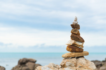 Fototapeta na wymiar Balanced stone pyramid on green water of ocean. life balance concept.
