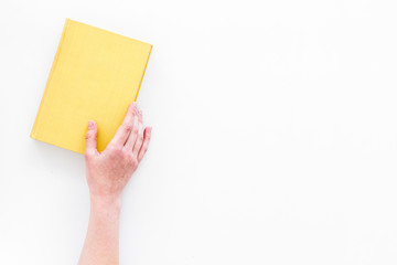 Reading for leasure. Hands take hardback book with empty cover on white background top view space...