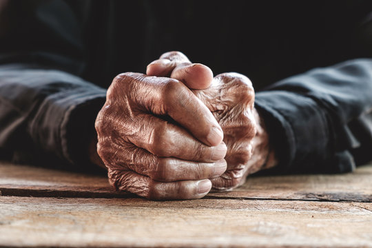 Hands of an old man on the wood table.vintage tone