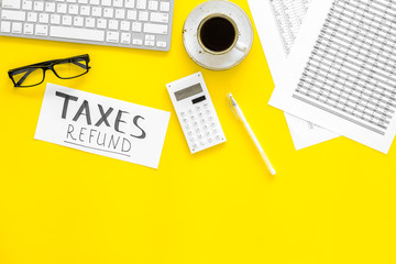 Taxes refund concept. Words taxes refund on office work desk with bills, keyboard, calculator on...