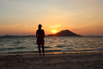 Fototapeta premium Woman silhouetted in front of sunset at the beach