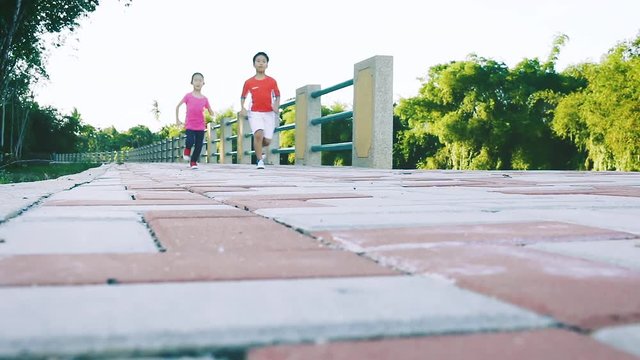 Asian children runner in sportswear jogging in public park.