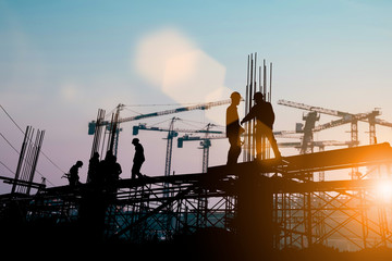 Silhouette of engineer and construction team working at site over blurred background sunset pastel...