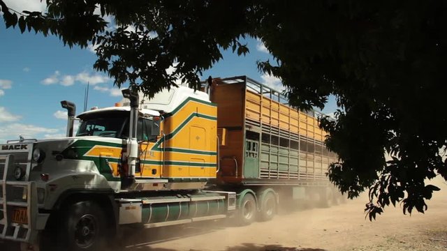 A medium shot of a big yellow truck carrying over a long cargo