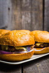 Tasty burger with basil on the rustic wooden background. Selective focus. Shallow depth of field.