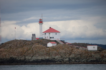 Fototapeta na wymiar Red roof lighthouse on a rocky island