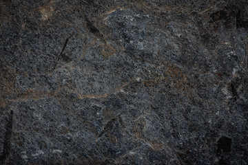 Close-up of dark stone texture featuring natural veining patterns and rough surface details. Ideal for backgrounds, architectural designs, and industrial-themed content.