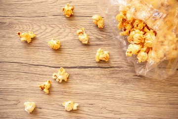 Sweet popcorn in plastic bag on the wooden table. The closeup food photo.