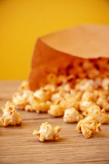 Sweet popcorn in brown paper bag on the wooden table. The closeup food photo