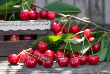Cherries with leaves in vintage wooden box on rustic wooden table. Copy space