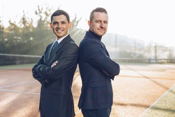Successful businessmen standing back to back