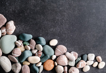 Fototapeta na wymiar Gas-colored sea pebbles on a gray granite background