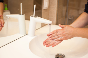 close up photo of woman washes her hands with soap and water