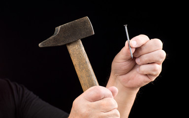 mains qui présentent marteau et clou isolé sur fond noir