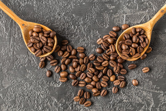 coffee beans in a wooden spoon on stone background.