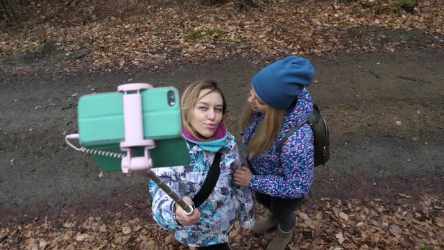 Cute blonde ladies girls friend hang out walking in forest enjoy taking selfie stick pictures