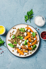 Lentil, roasted vegetables and goat cheese salad on light blue background. Top view, copy space.