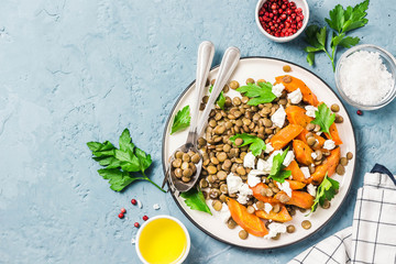 Lentil, roasted vegetables and goat cheese salad on light blue background. Top view, copy space.