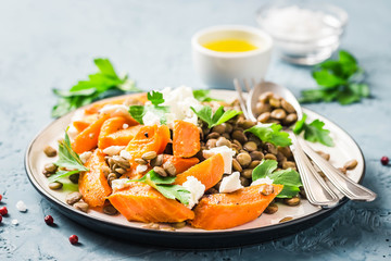 Lentil, roasted vegetables and goat cheese salad on light blue background. Selective focus, copy space.