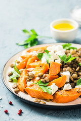 Lentil, roasted vegetables and goat cheese salad on light blue background. Selective focus, copy space.