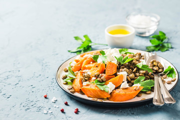 Lentil, roasted vegetables and goat cheese salad on light blue background. Selective focus, copy space.