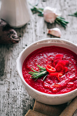 Beet cream soup with rosemary, garlic and chili on wooden background