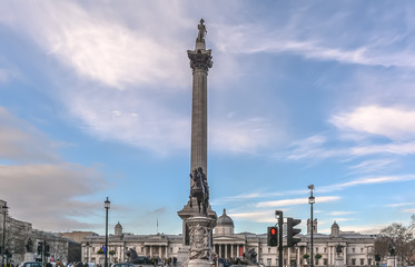 View to the tall Nelson's Column in Trafalgar Square in central London against blue cloudy sky.