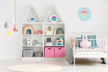 Colorful lamps above rug in modern scandi kid's bedroom interior with poster above bed