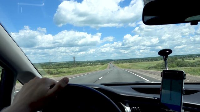 man is driving a car at high speed and holds the wheel with his hand. Road, blue sky. 