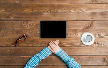 Top view of woman sitting at wooden table with hands folded