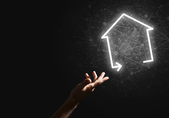 Conceptual image with hand pointing at house or main page icon on dark background