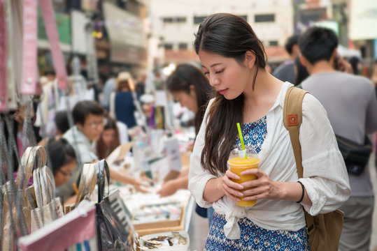 woman holding a cup of mango juice and shopping