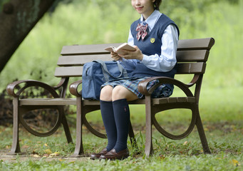 Fototapeta premium ベンチで本を読む女子高生
