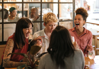 Diverse group of girlfriends laughing together in a trendy bar