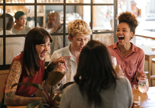 Diverse Group Of Girlfriends Laughing Together In A Trendy Bar