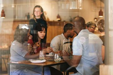 Diverse young friends eating together at a bistro table