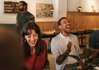 Diverse young friends laughing together during a restaurant dinner