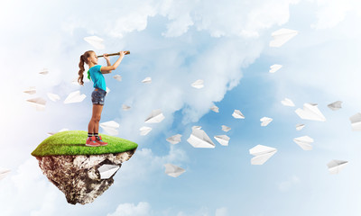 Concept of careless happy childhood with girl looking in spyglass