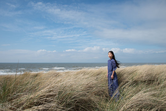 Teen girl standing in tall grass on sea coast