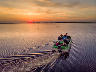 Tourists visiting Danube Delta in a motor boat, taking pictures at sunset in the Danube Delta,...