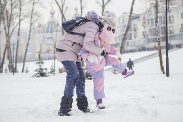 Fototapeta na wymiar Happy loving caucasian family of mother father and daughter play, having fun in winter snowy park. Cute little girl playing