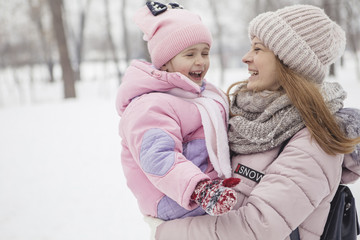 Happy loving caucasian family of mother father and daughter play, having fun in winter snowy park