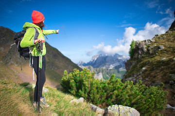 Girl during an alpine trek signals a mountain peak