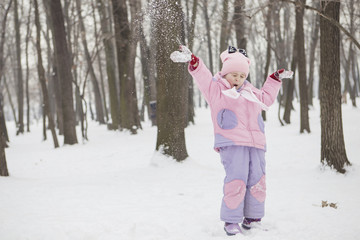 Happy loving caucasian family of mother father and daughter play, having fun in winter snowy park. Cute little girl playing