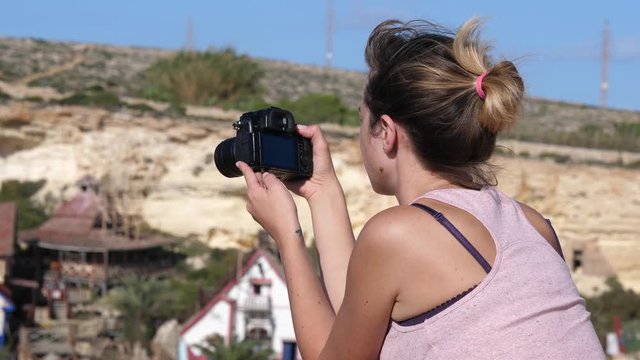 Young woman tourist takes pictures with photo camera traveling to Malta