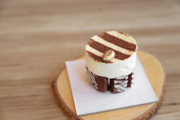 Tiramisu cake recipe with golden coffee bean decorated on top on wooden plate.
